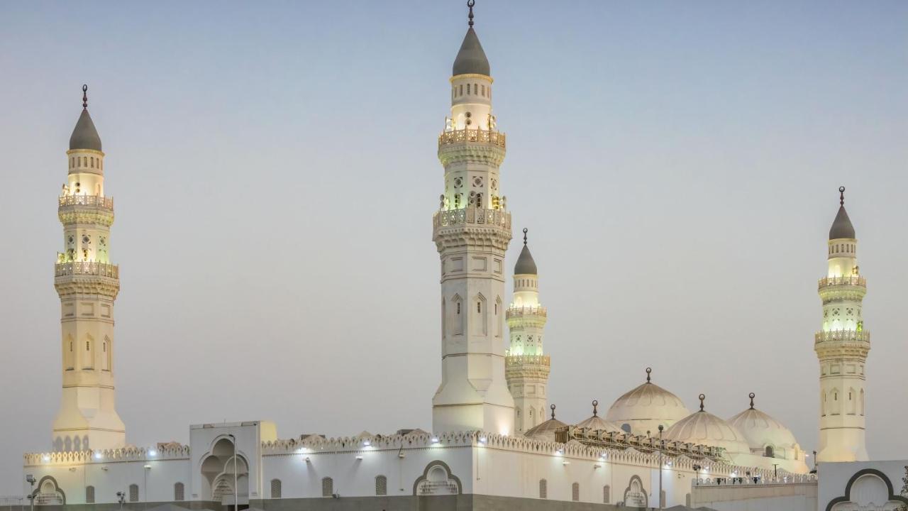 Hotel Intercontinental Dar Al Iman Madinah By Ihg Medina Exterior foto The image shows a mosque with distinct architectural features, including tall minarets and domes. The minarets are highlighted, likely lit up in the evening, showcasing intricate design elements typical of Islamic architecture. The overall scene conv
