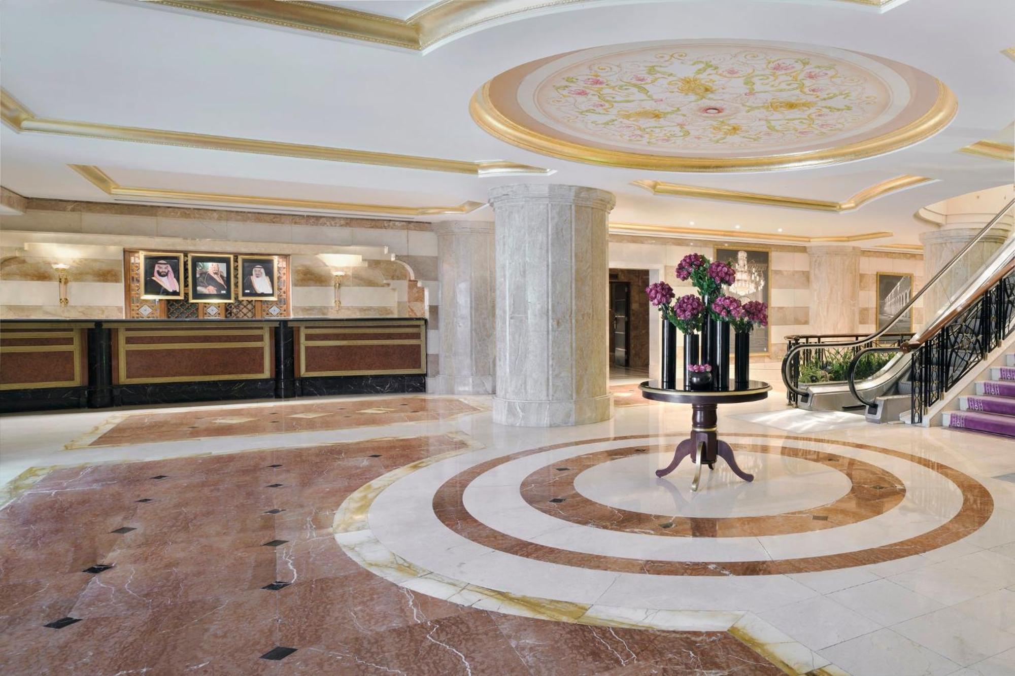 Hotel Intercontinental Dar Al Iman Madinah By Ihg Medina Exterior foto The photo shows a luxurious hotel lobby. The space features elegant marble flooring with circular designs, complemented by a large, decorative ceiling. In the center, there is a round table adorned with a floral arrangement. Behind the table, a recep