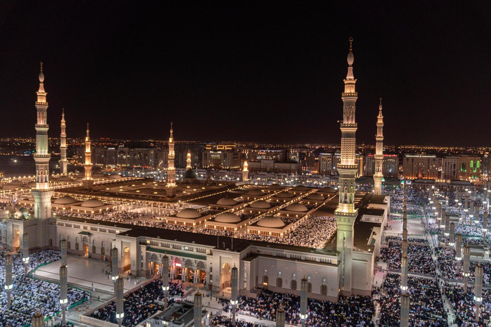 Hotel Intercontinental Dar Al Iman Madinah By Ihg Medina Exterior foto The photo shows a panoramic view of a large mosque complex illuminated at night. It features tall minarets with lights, a vast courtyard filled with people, and a beautifully lit architectural design. The overall ambiance suggests a significant space