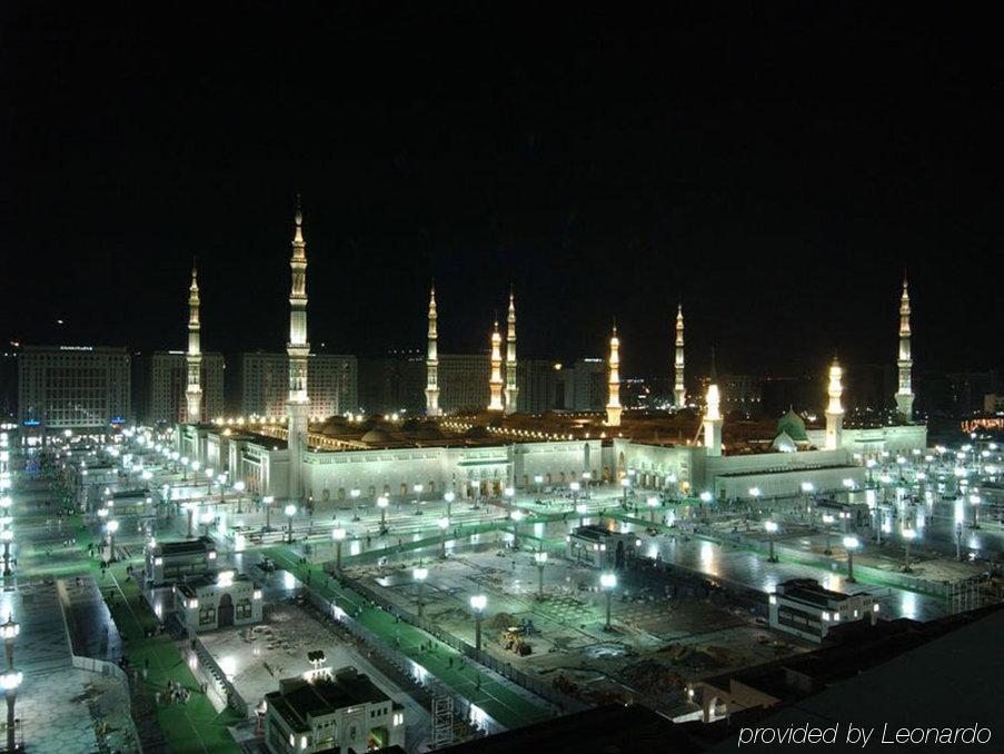 Hotel Intercontinental Dar Al Iman Madinah By Ihg Medina Servicios foto The image shows the illuminated landscape of a mosque complex at night. It features several tall minarets, which are typically part of Islamic architecture, adorned with lights. The mosque's central building is also brightly lit, surrounded by an ope