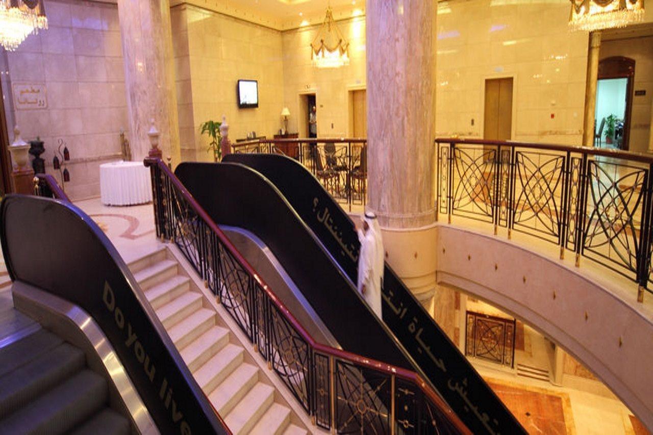 Hotel Intercontinental Dar Al Iman Madinah By Ihg Medina Interior foto The photo depicts an elegant interior space, likely within a hotel or a large building. There is a grand staircase visible, which features a combination of stairs and escalators. The design includes decorative railings and marble pillars, contributin